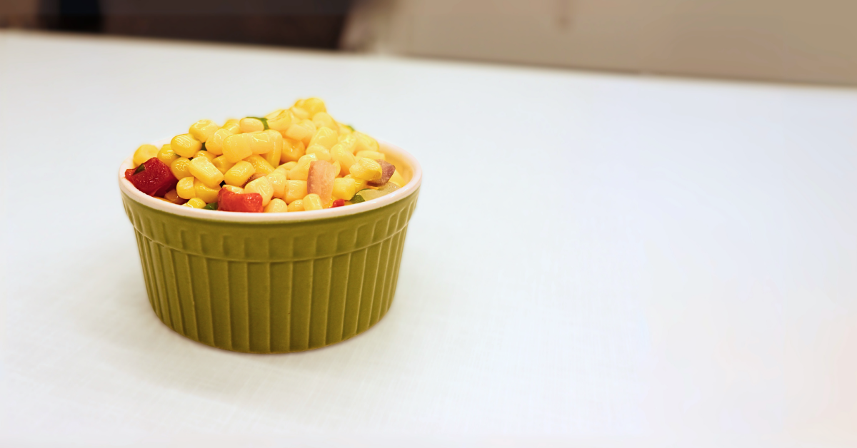 Image of Chuck Wagon Corn in a green ramekin for a Feed More post sharing two versions of a budget-friendly summer side dish recipe.