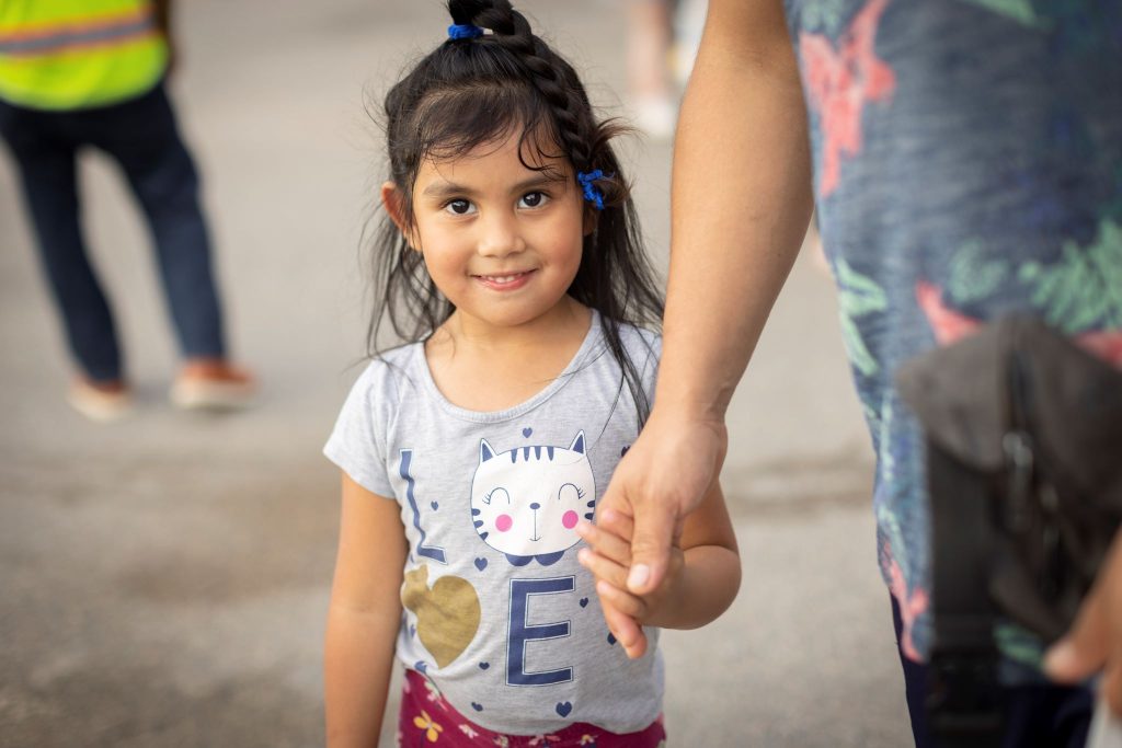 Little girl holding her dad's hand while at a food pantry