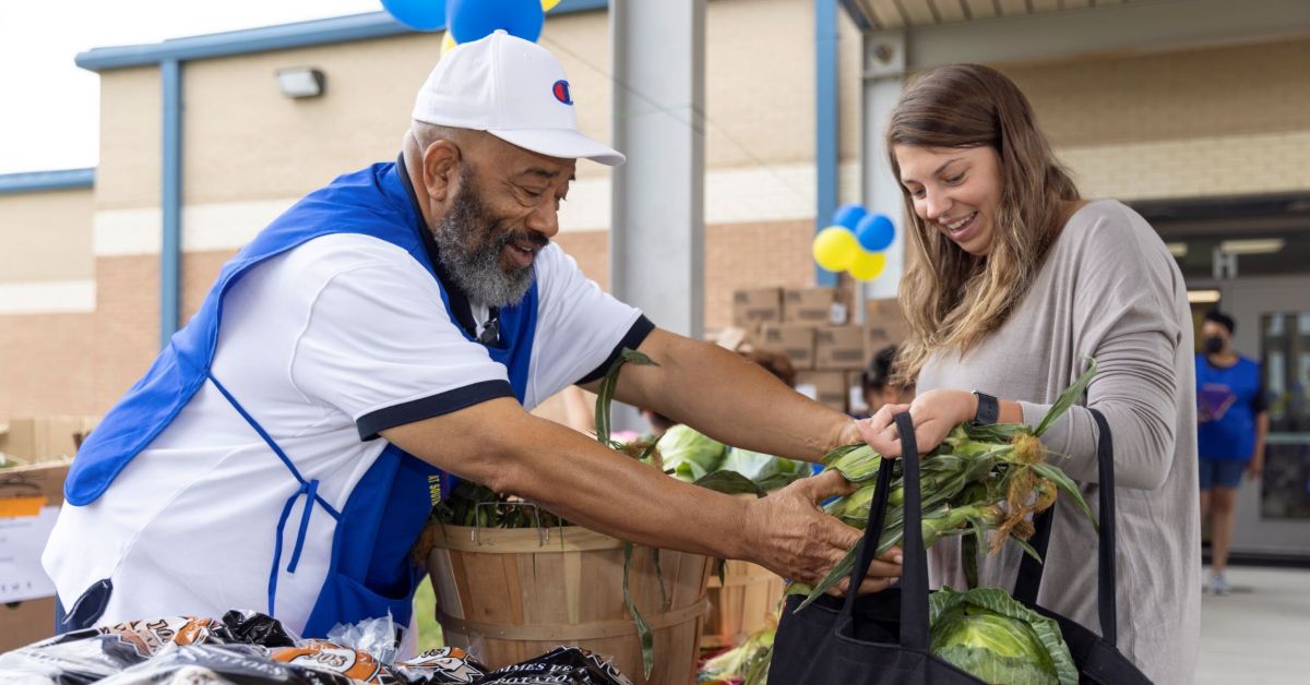 Man putting healthy food into a woman's bag. The food was provided by Feed More thanks to the community's help.