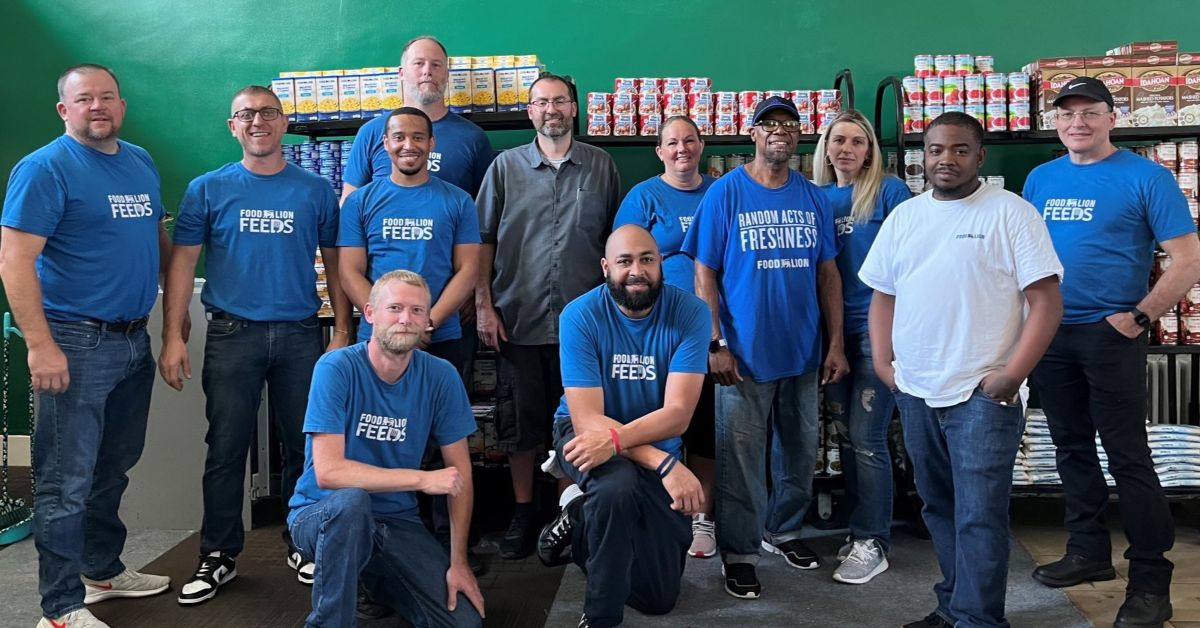 Group of men in blue Food Lion Feeds shirts at a Feed More partner agency pantry.