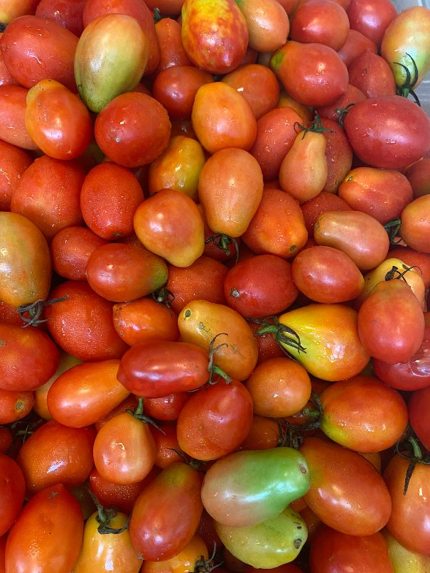 A box filled with fresh, ripe tomatoes, from Feed More's services .