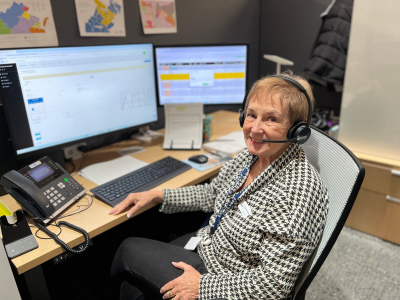 Woman sitting at computer desk with headset to take phone calls. 